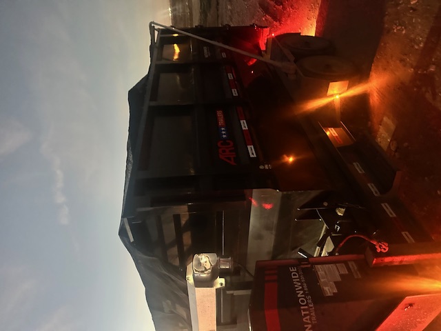 SD Services truck towing a black trash trailer on a jobsite road.